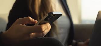 man-holding-phone-with-girl-in-background